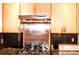A well-equipped kitchen with wood cabinets, stainless steel backsplash, black countertops, and a gas cooktop at 2929 Matoka Trl, Matthews, NC 28104