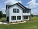 Beautiful two-story home with white siding, black trim, complemented by professionally landscaped yard at 3012 Isle Ln, Monroe, NC 28110
