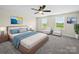 A bright main bedroom featuring plush carpeting, a ceiling fan, sitting area, and natural light from two windows at 3012 Isle Ln, Monroe, NC 28110