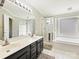 Bright bathroom featuring a double sink vanity, soaking tub, and a glass-enclosed shower at 3017 Planters Walk Ct, Charlotte, NC 28210