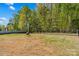 Spacious backyard featuring a fire pit, privacy fence, and lush trees at 320 Silver Oak Cir, Rockwell, NC 28138