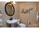 Elegant powder room featuring stylish fixtures, an ornate mirror, and decorative wall art at 3404 Pasture View Ct, Charlotte, NC 28269