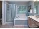 Bright bathroom featuring a glass-enclosed shower, large soaking tub, and a window for natural light at 3404 Pasture View Ct, Charlotte, NC 28269