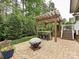 Outdoor kitchen with pergola, stainless steel appliances, seating, and nearby fire pit in a lush backyard at 358 Hampton Trail Dr, Fort Mill, SC 29708