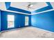Spacious bedroom with blue walls, tray ceiling, ceiling fan, and natural light from two windows at 6728 Mimosa St, Indian Trail, NC 28079