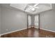 Spacious bedroom with tray ceiling, ceiling fan, and two windows with floral print curtains at 7502 Hurstbourne Green Dr, Charlotte, NC 28277
