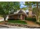 Brick home's side view featuring mature trees, tidy landscaping, and a charming brick gate entrance at 7502 Hurstbourne Green Dr, Charlotte, NC 28277