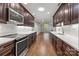 Galley kitchen featuring stainless steel appliances, dark cabinetry, white subway tile backsplash and light countertops at 7502 Hurstbourne Green Dr, Charlotte, NC 28277