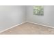 This bedroom features neutral carpet and a large window providing ample natural light at 7507 Holly Grove Ct, Charlotte, NC 28227