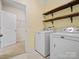 Bright laundry room featuring a washer and dryer with convenient rustic wood shelving for storage at 797 Latrobe Dr, Iron Station, NC 28080