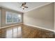 Neutral bedroom with hardwood floors, a ceiling fan, and a large window at 802 Capington Ln, Waxhaw, NC 28173