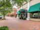 Charming street view of a shopping center with brick sidewalks and retail storefronts under green awnings at 8065 Cornhill Ave, Charlotte, NC 28277