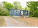 Charming blue single-story home featuring a gravel driveway surrounded by lush green trees at 1011 Rickert St, Statesville, NC 28677