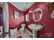 Charming bathroom featuring a pedestal sink, toilet, and wall mirror, with red accents at 110 Devonshire Ln, Salisbury, NC 28146