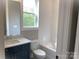 Bathroom featuring a blue vanity with marble top, subway tiled walls, window, and a tub at 117 Blackbeard Ln, Mooresville, NC 28117