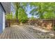 Large backyard with brick pavers, a wood deck, privacy fence, and lush greenery for outdoor enjoyment at 1716 Wickford Pl, Charlotte, NC 28203