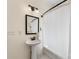 The bright bathroom features a pedestal sink and tub with shower, enhanced by a black framed mirror at 1716 Wickford Pl, Charlotte, NC 28203