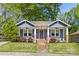 Charming blue home with a quaint front porch, swing, brick accents, and beautiful landscaping at 1716 Wickford Pl, Charlotte, NC 28203