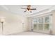 Bright bedroom featuring tray ceiling, ceiling fan, large window, and neutral colored walls and carpet at 20135 Dovekie Ln, Fort Mill, SC 29707