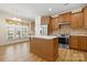 Well-lit kitchen featuring wood cabinets, stainless steel appliances, tile backsplash, and central island at 20135 Dovekie Ln, Fort Mill, SC 29707