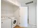 Functional laundry room features white appliances, shelving, and connecting doorway at 2141 Talbert Ct, Charlotte, NC 28214