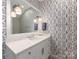 Well-lit powder room featuring a white vanity, modern mirror, and patterned wallpaper at 2343 Vernon Dr, Charlotte, NC 28211