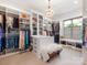 Spacious walk-in closet featuring custom shelving, drawers, and a decorative chandelier at 2343 Vernon Dr, Charlotte, NC 28211