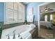 Bathroom with garden tub with tiled surround, window with shutters, and towel warmer at 2355 Crockett Park Pl, Charlotte, NC 28203