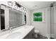 Bright bathroom with double vanity, sleek lighting, shower with glass doors and window with verdant outdoor view at 2601 Pinewood Rd, Gastonia, NC 28054