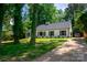 Charming single-story home with a brick exterior, lush landscaping, and a private driveway surrounded by mature trees at 2601 Pinewood Rd, Gastonia, NC 28054