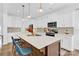 Bright kitchen features an island with seating, white cabinets, and stainless steel appliances at 3153 Pinehills Way, Mount Holly, NC 28120
