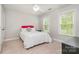 Well-lit bedroom with two windows, soft carpet, and a comfortable bed with colorful pillows at 3306 Delamere Dr, Matthews, NC 28104
