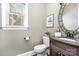 Elegant powder room featuring marble vanity, decorative mirror, and natural light at 3306 Delamere Dr, Matthews, NC 28104