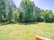 Large backyard with a fire pit and surrounded by trees, perfect for outdoor entertaining and relaxation at 3546 Mount Pleasant N Rd, Concord, NC 28025
