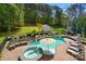 Backyard featuring a pool, spa, stone fireplace and lounge chairs surrounded by lush greenery at 4160 Isle Of Pines Dr, Denver, NC 28037