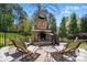 A charming outdoor brick fireplace with stone accents on a brick patio surrounded by mature trees at 4160 Isle Of Pines Dr, Denver, NC 28037