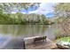 Peaceful lake view from a wooden dock, complete with a bench seat and row boat, perfect for relaxing outdoors at 455 W Gleneagles Rd, Statesville, NC 28625
