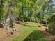 A lush backyard with a swing set and mature trees on a sunny day at 5601 Londonderry Rd, Charlotte, NC 28210
