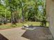 A brick patio with furniture, set in a green lawn with mature trees at 5601 Londonderry Rd, Charlotte, NC 28210