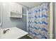 This blue bathroom features a vanity, a mirror with lights, overhead storage and a shower with blue pattern curtain at 621 Harper Davis Rd, Lake Wylie, SC 29710
