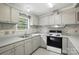 The kitchen features a double sink, stone backsplash, window and ample counter space near the black and white stove at 621 Harper Davis Rd, Lake Wylie, SC 29710