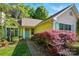 Charming yellow home with lush landscaping, including flowering shrubs, mature trees, and a well-manicured lawn at 6307 Old Corral St, Charlotte, NC 28277
