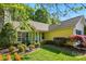Charming yellow home with lush landscaping, including flowering shrubs, mature trees, and a well-manicured lawn at 6307 Old Corral St, Charlotte, NC 28277