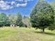 Expansive green backyard with mature trees and small storage building featuring lawn equipment and tools at 6401 Alley Rd, Catawba, NC 28609
