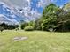 Expansive green backyard, dotted with trees and featuring a circular fire pit area, perfect for outdoor entertaining and relaxation at 6401 Alley Rd, Catawba, NC 28609