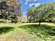 A beautifully manicured backyard features lush, green grass and mature trees against a bright blue sky with fluffy white clouds at 6401 Alley Rd, Catawba, NC 28609