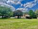 Back exterior showcasing a ranch-style home with lush green lawn and mature trees on a sunny day with cloudy skies at 6401 Alley Rd, Catawba, NC 28609