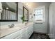 Bright bathroom featuring a double sink vanity, decorative mirrors, a window, and stylish gray walls at 6726 Park Meadows Pl, Huntersville, NC 28078