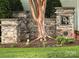 Stone entrance to the property featuring a black and gold sign with manicured landscaping and a mature tree at 6726 Park Meadows Pl, Huntersville, NC 28078