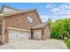 Attached three-car garage featuring brick exterior, lighting, and a concrete driveway at 8169 Clems Branch Rd, Indian Land, SC 29707